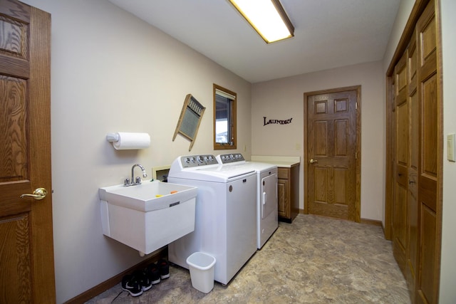 laundry room with cabinet space, baseboards, a sink, and independent washer and dryer