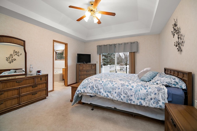 bedroom featuring access to exterior, a raised ceiling, light colored carpet, and a ceiling fan