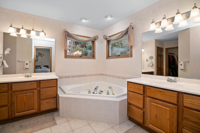 full bath featuring a jetted tub, two vanities, a sink, and tile patterned floors