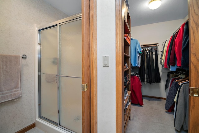 bathroom with a shower stall, a spacious closet, and baseboards