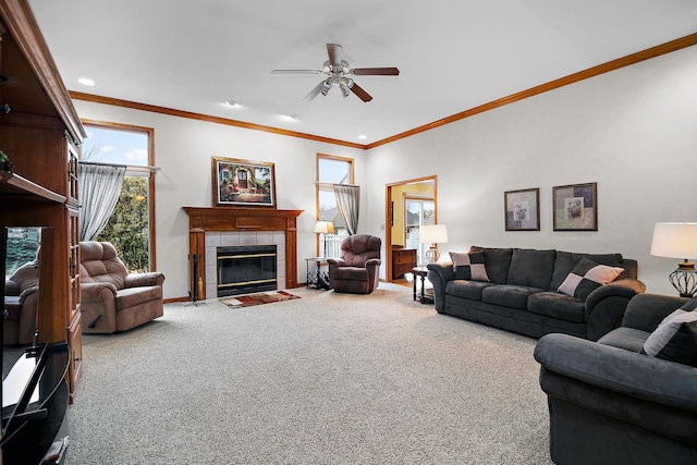 living area featuring baseboards, a ceiling fan, ornamental molding, carpet flooring, and a fireplace