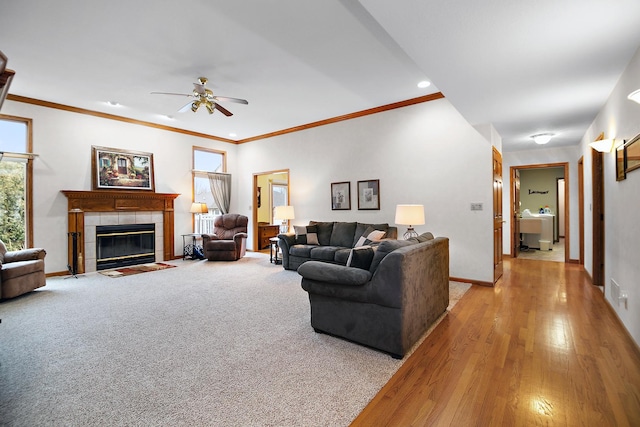 living room with baseboards, ceiling fan, a tiled fireplace, and a healthy amount of sunlight