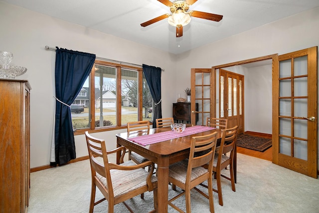 dining room featuring light carpet, baseboards, a ceiling fan, and french doors