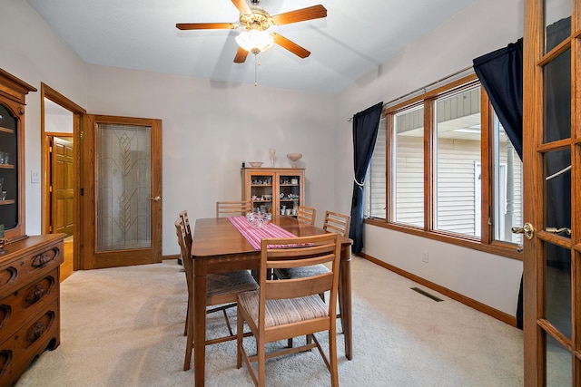 dining area with a ceiling fan, light carpet, visible vents, and baseboards