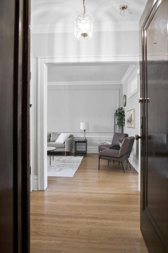 sitting room with ornamental molding, an inviting chandelier, and wood finished floors