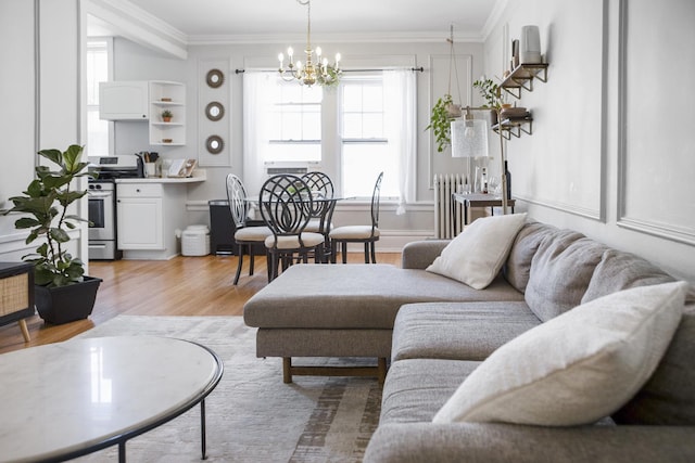 living area featuring radiator, light wood-style flooring, ornamental molding, and a chandelier