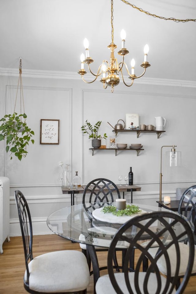 dining space featuring radiator heating unit, a decorative wall, crown molding, and wood finished floors