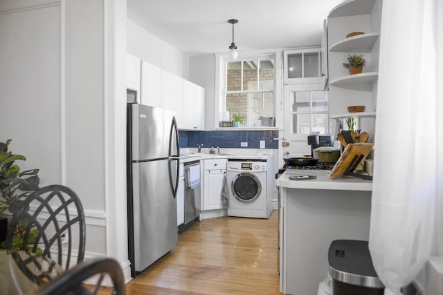 kitchen with stainless steel appliances, white cabinetry, light wood-style floors, light countertops, and washer / dryer