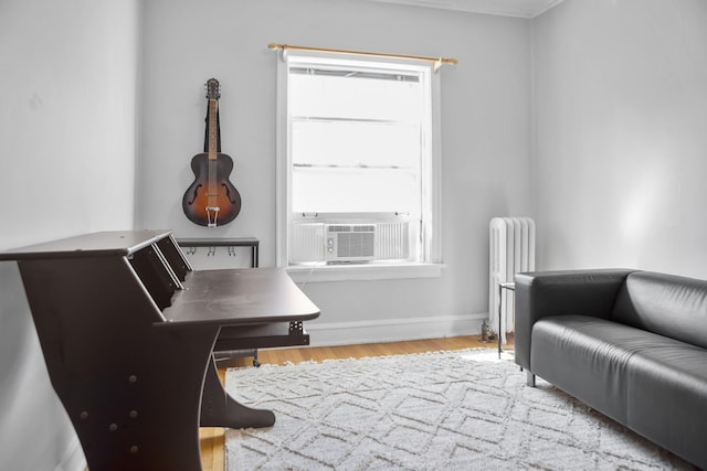 sitting room featuring baseboards, wood finished floors, cooling unit, and radiator