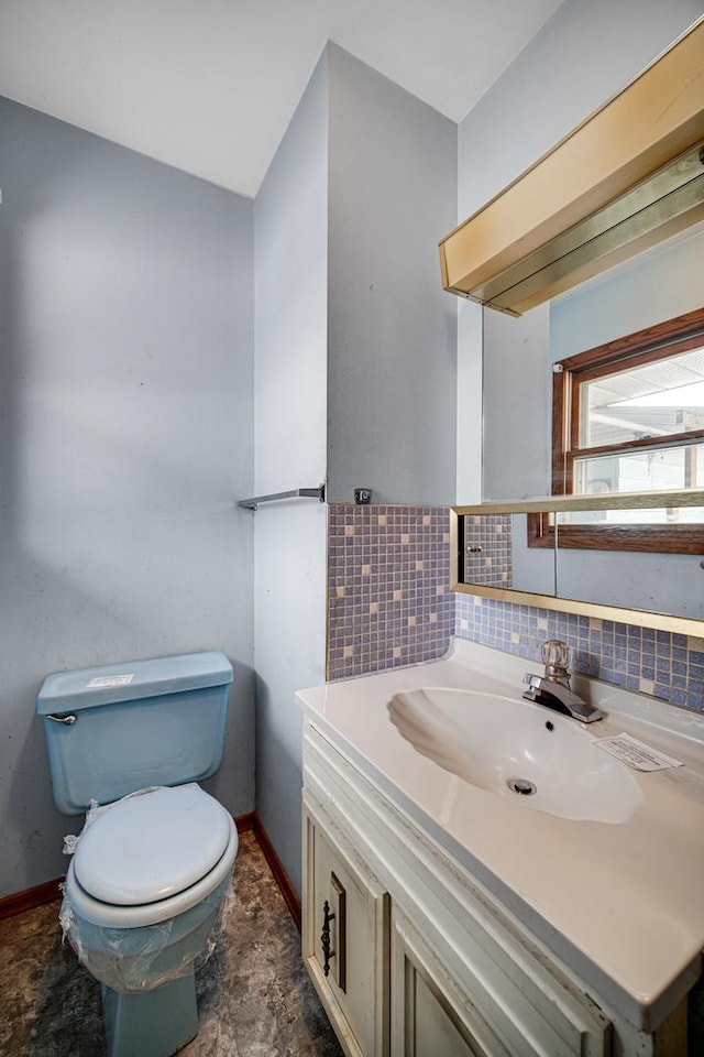 bathroom featuring backsplash, baseboards, vanity, and toilet