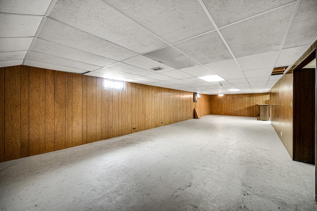 below grade area featuring a paneled ceiling, visible vents, and wooden walls