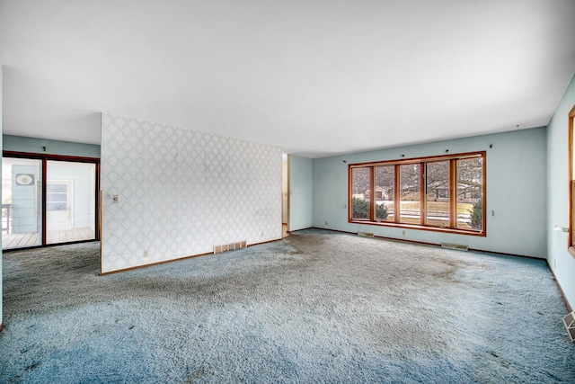 carpeted spare room with baseboards, visible vents, and wallpapered walls