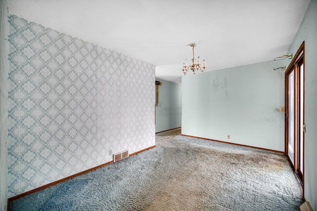 carpeted empty room featuring a notable chandelier, baseboards, visible vents, and wallpapered walls