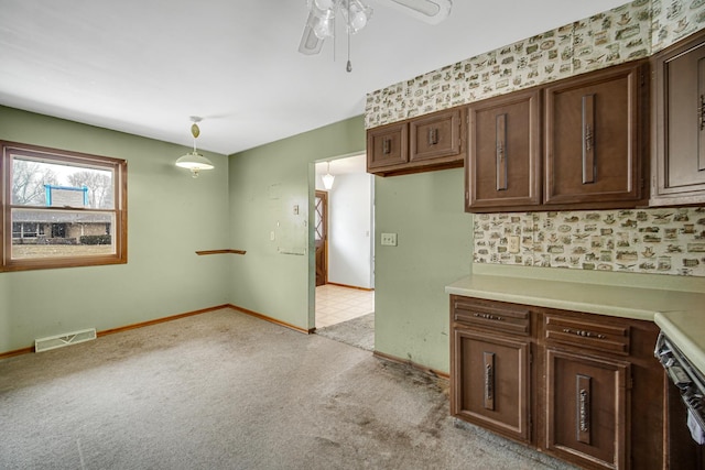 kitchen featuring dark brown cabinetry, light colored carpet, visible vents, baseboards, and light countertops