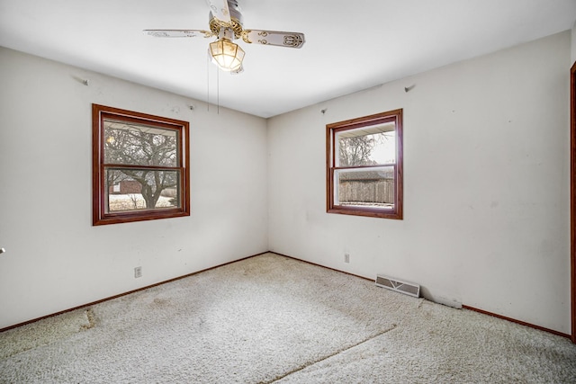 carpeted empty room featuring visible vents, ceiling fan, and baseboards