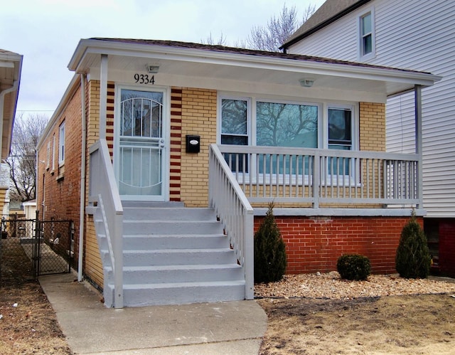 view of front facade with a gate, a porch, and brick siding