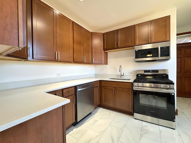 kitchen featuring marble finish floor, stainless steel appliances, a sink, and light countertops