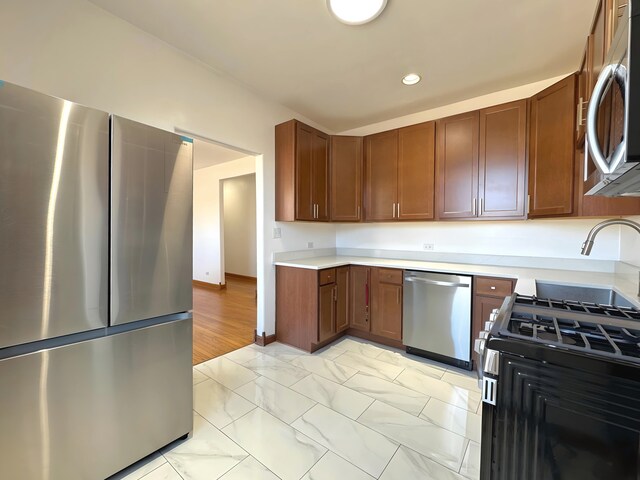 kitchen featuring recessed lighting, baseboards, marble finish floor, light countertops, and appliances with stainless steel finishes