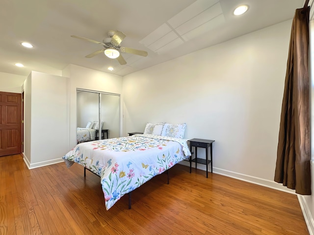 bedroom with recessed lighting, a closet, a ceiling fan, wood finished floors, and baseboards