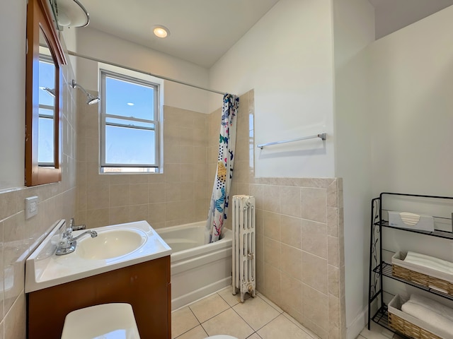 full bath with tile walls, radiator heating unit, shower / bath combo with shower curtain, vanity, and tile patterned floors