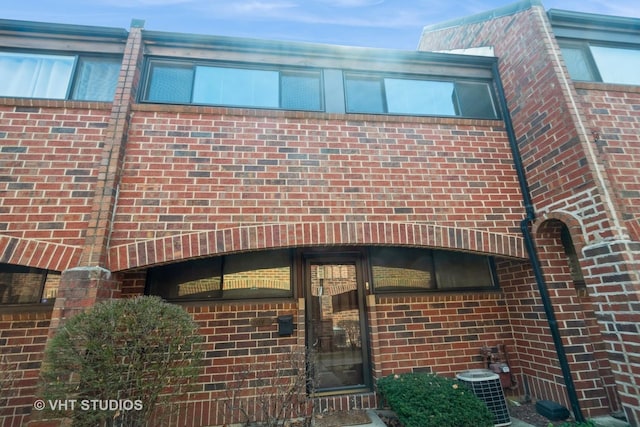 exterior space with cooling unit and brick siding