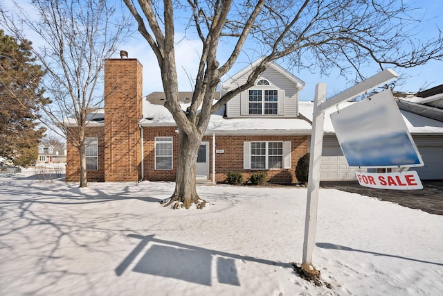 view of front facade featuring a garage, driveway, a chimney, and brick siding