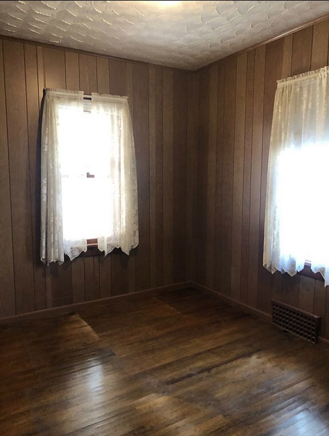 spare room featuring wooden walls, visible vents, and dark wood-style flooring