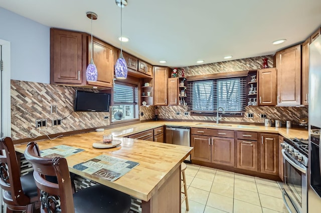 kitchen with a breakfast bar area, open shelves, appliances with stainless steel finishes, a sink, and a peninsula