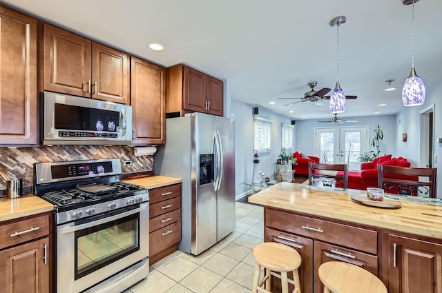 kitchen with backsplash, stainless steel appliances, wooden counters, and french doors