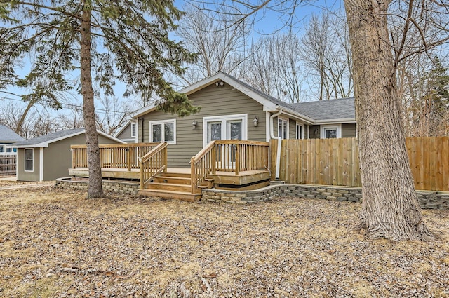 back of house featuring a deck, roof with shingles, and fence