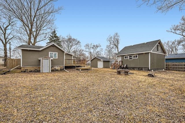 view of yard with a deck, an outbuilding, a fire pit, fence, and a shed