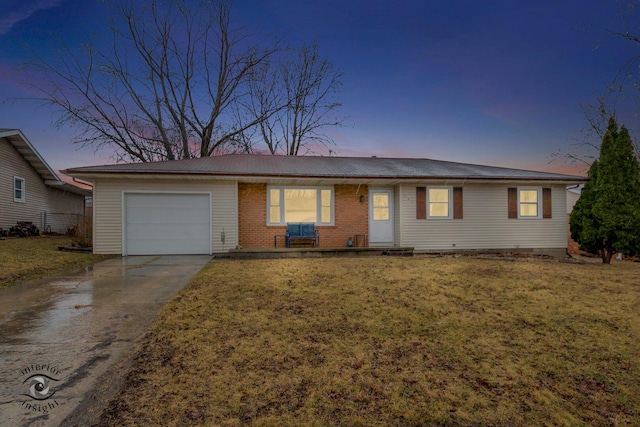 single story home with a garage, driveway, a yard, and brick siding