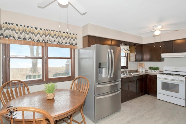 kitchen with stainless steel refrigerator with ice dispenser, a sink, white range with gas cooktop, dark brown cabinets, and under cabinet range hood