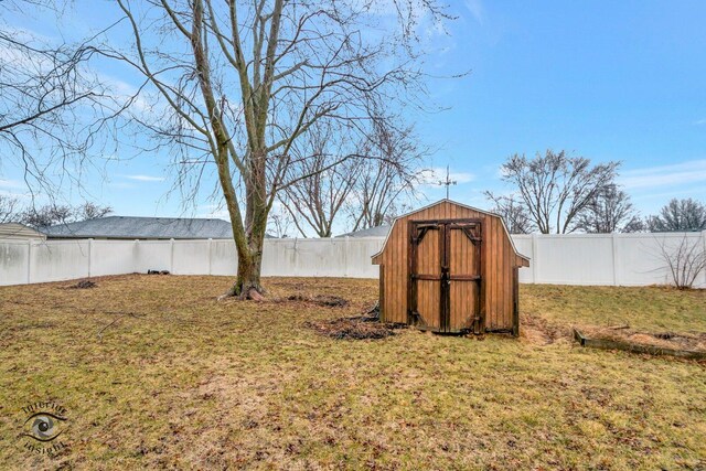 view of yard with a storage shed, a fenced backyard, and an outdoor structure