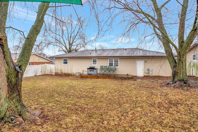 rear view of house with a wooden deck, fence, and a yard