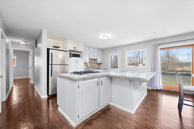 kitchen featuring appliances with stainless steel finishes, dark wood-style flooring, a center island, open shelves, and backsplash