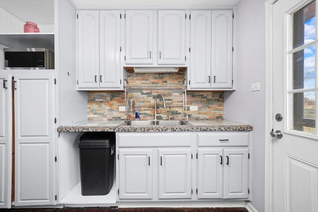 kitchen with plenty of natural light, white cabinetry, decorative backsplash, and a sink