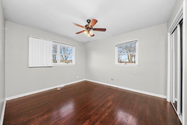 unfurnished bedroom with a closet, dark wood finished floors, a ceiling fan, and baseboards