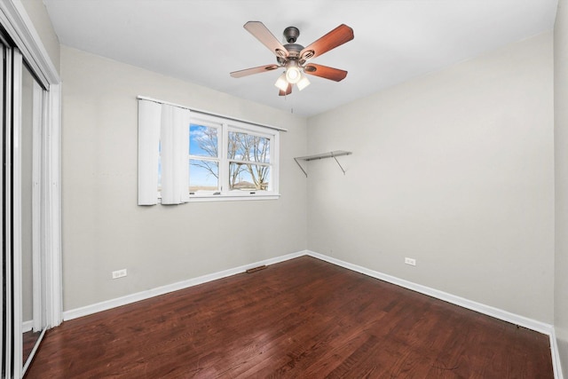 unfurnished bedroom featuring a closet, wood finished floors, a ceiling fan, and baseboards