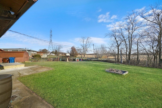 view of yard featuring a storage shed, fence, a playground, and an outdoor structure