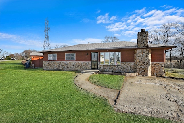 view of front of house featuring stone siding, a chimney, and a front yard