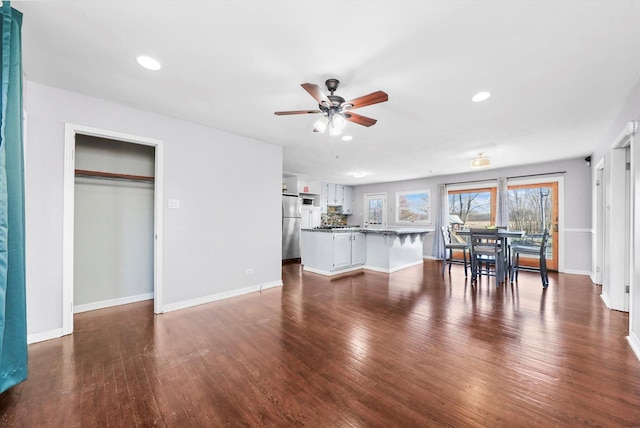 unfurnished living room with dark wood-style floors, ceiling fan, baseboards, and recessed lighting