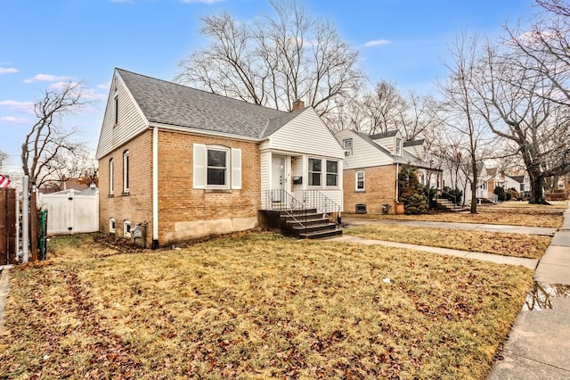 bungalow with brick siding, fence, a chimney, and roof with shingles