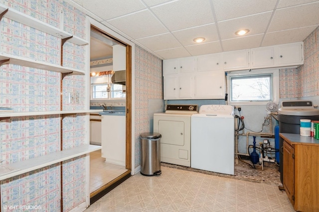 laundry room featuring wallpapered walls, light floors, cabinet space, independent washer and dryer, and a sink