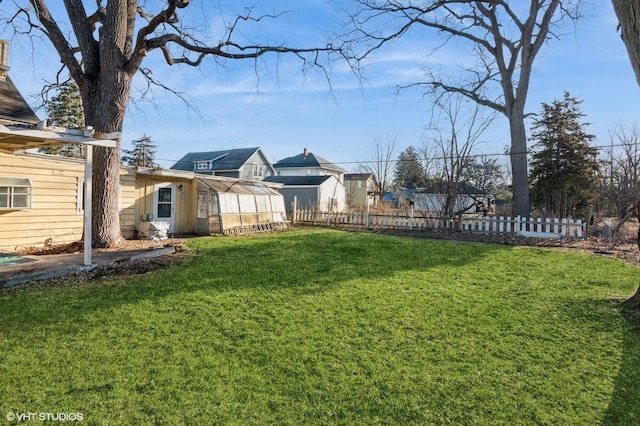 view of yard featuring a greenhouse, fence private yard, and an outdoor structure