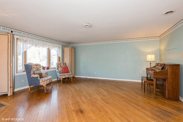 living area featuring hardwood / wood-style flooring, visible vents, and baseboards