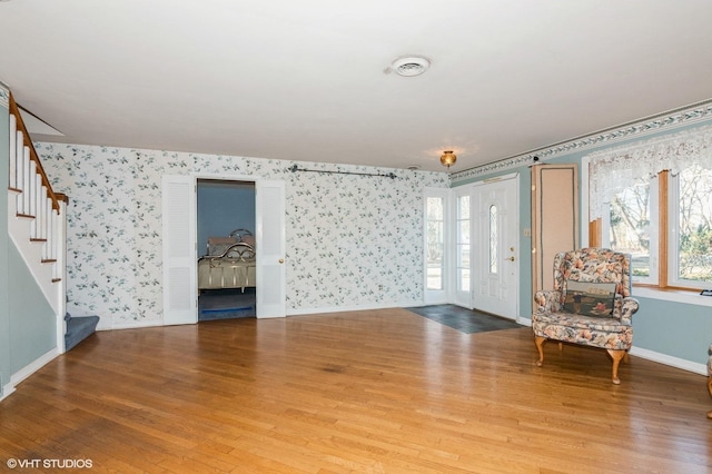 interior space with wallpapered walls, stairs, baseboards, and wood finished floors