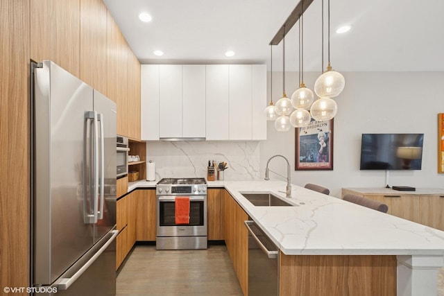 kitchen featuring stainless steel appliances, a sink, a peninsula, and modern cabinets