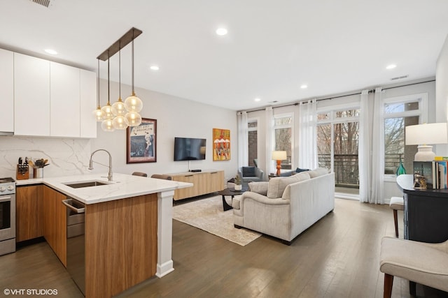 kitchen with light stone countertops, a sink, a peninsula, and modern cabinets