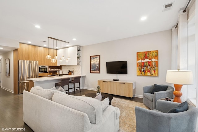 living area with dark wood-type flooring, recessed lighting, visible vents, and baseboards